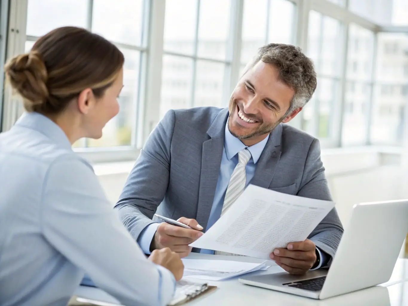 A professional in a well-lit office is reviewing tax documents with a client, both smiling and engaged in a discussion about tax strategies.